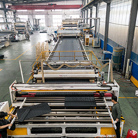 Workers operating an advanced automated extrusion line, manufacturing black HDPE ground protection mats with anti-slip diamond tread.