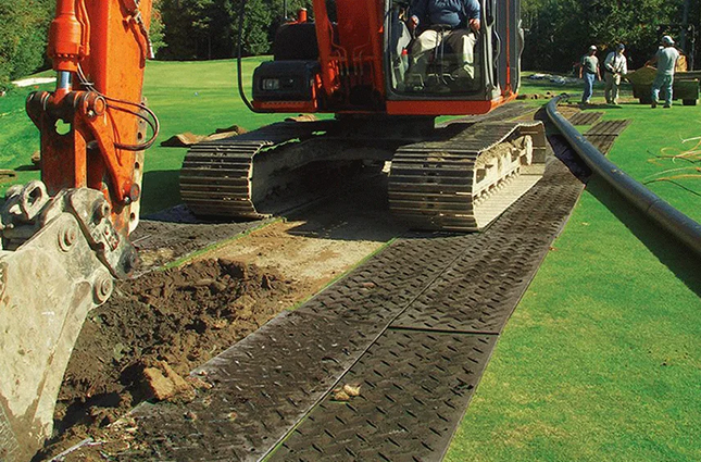 Products HDPE ground protection mats preventing ruts as a heavy excavator drives across grass and soft terrain